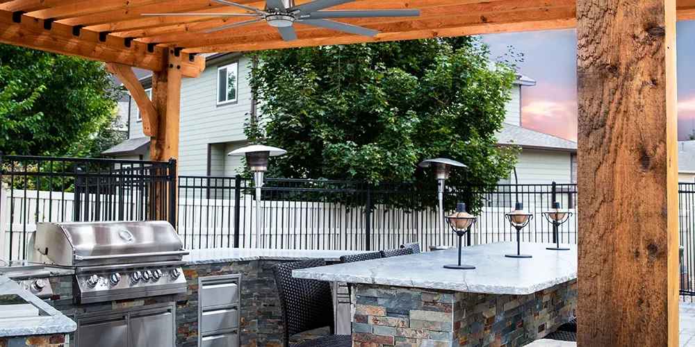 wooden pergola with ceiling fan and outdoor kitchen