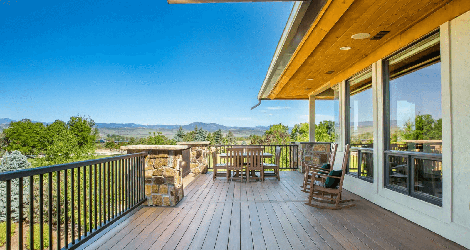 Spacious composite deck with a scenic mountain view, stone accents, black metal railings, and an outdoor dining area.