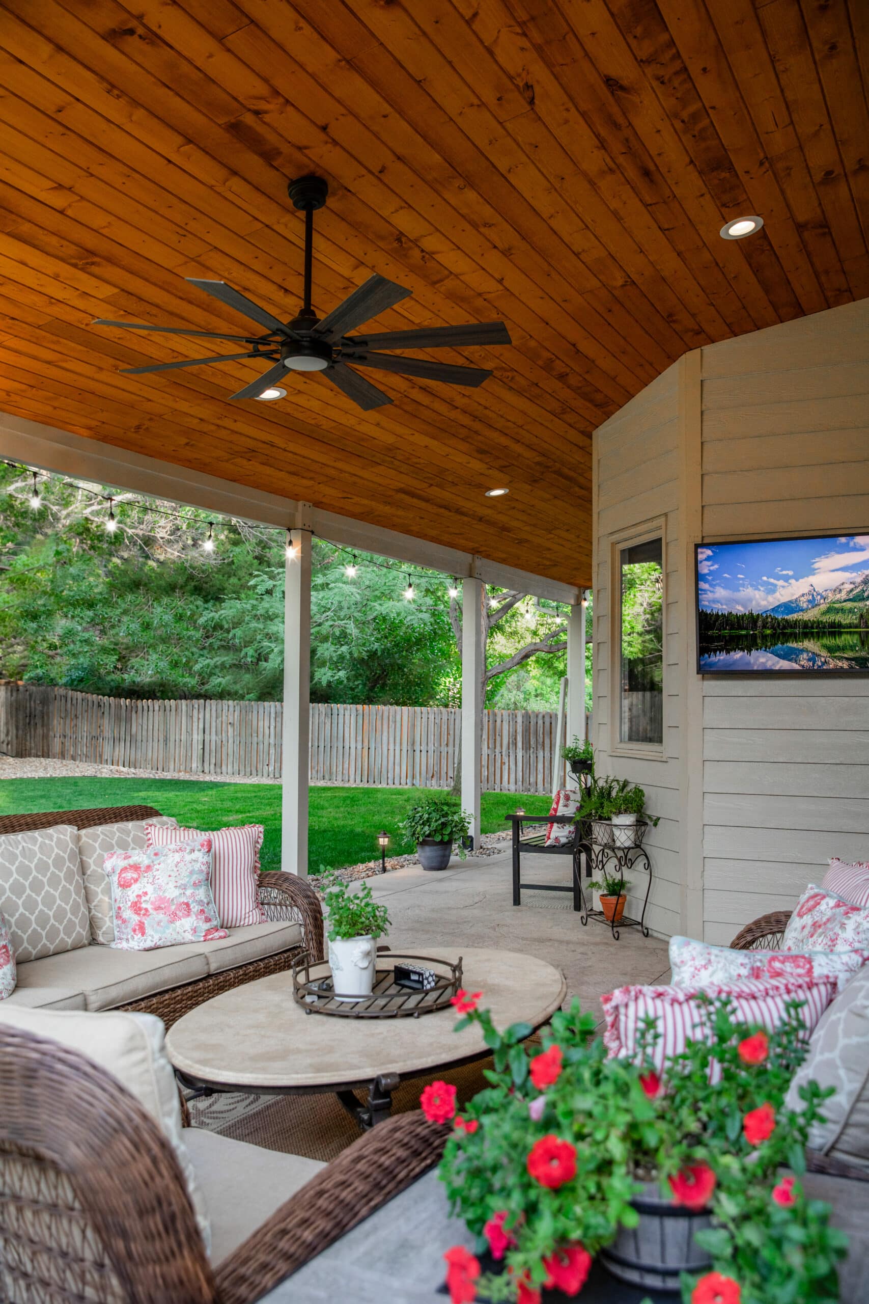 remodeled open patio that was converted into a veranda with an outdoor living room area with mounted TV and ceiling fans.