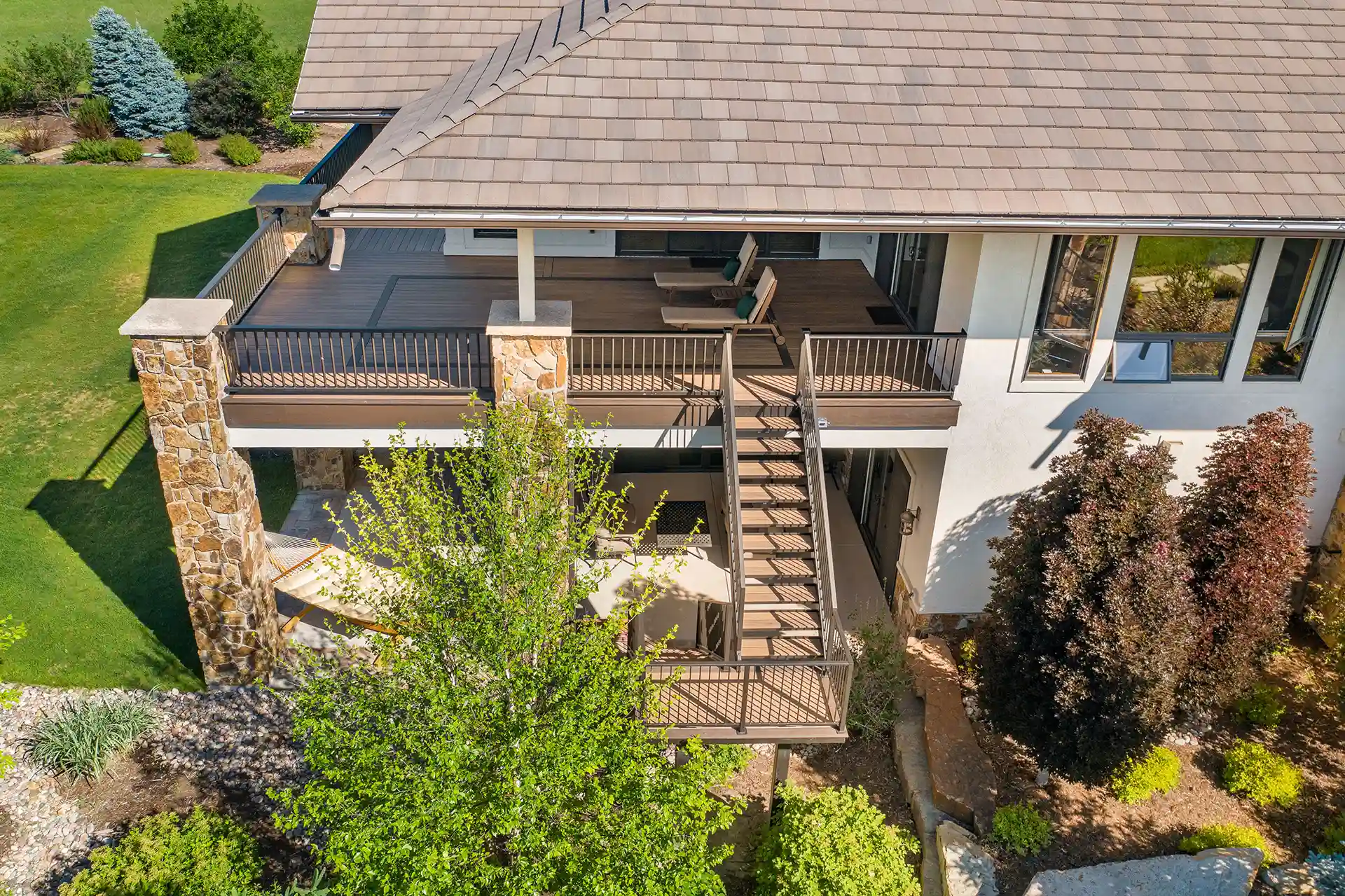 Multi-level deck with a covered lower patio, metal railings, and an exterior staircase leading to the upper deck.