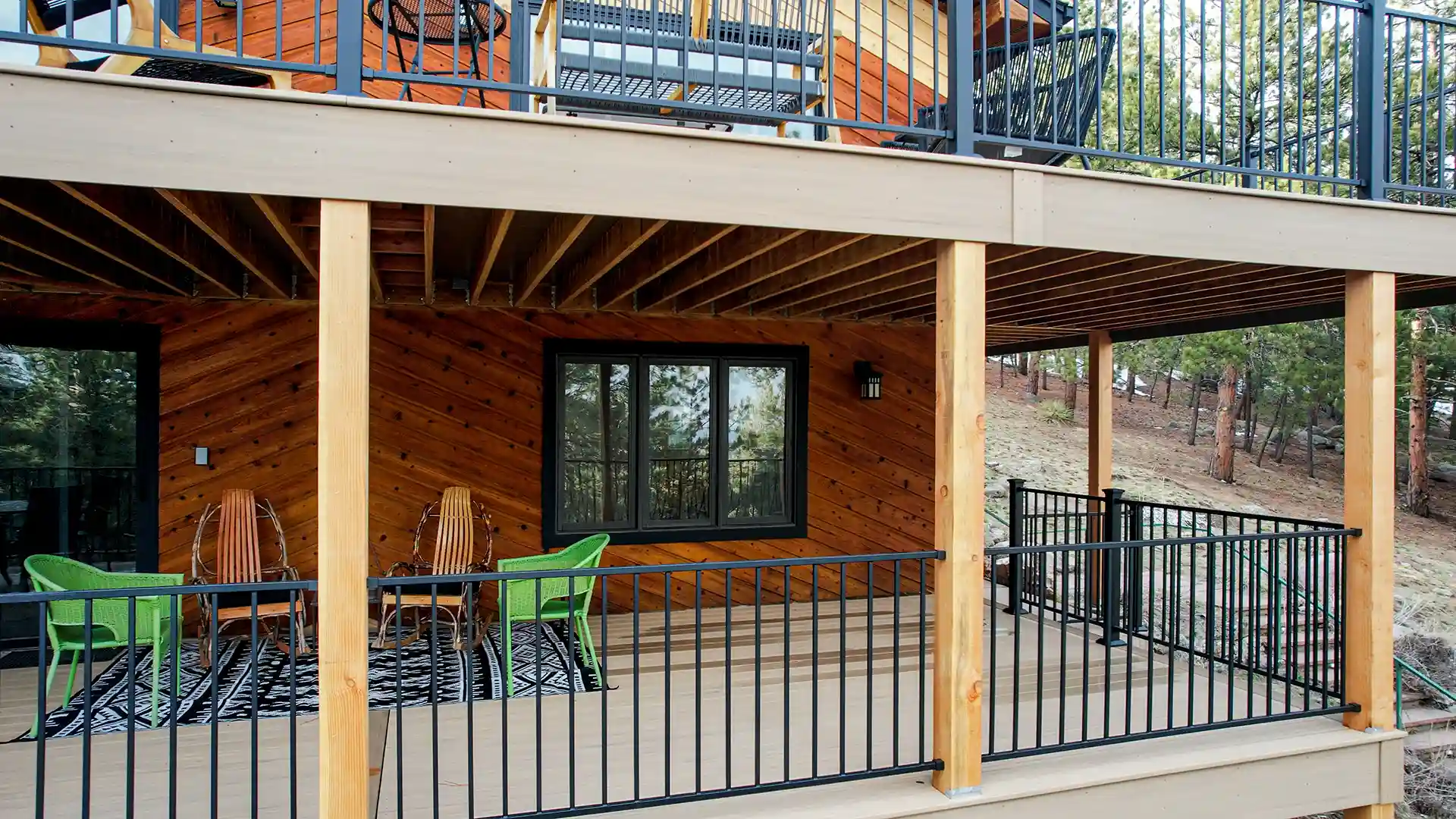 Two-story deck with black metal railings, wood posts, and a cozy lower-level seating area.