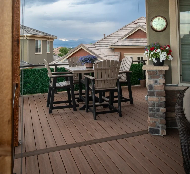Shaded outdoor deck with dining table and chairs overlooking a neighborhood and mountains.